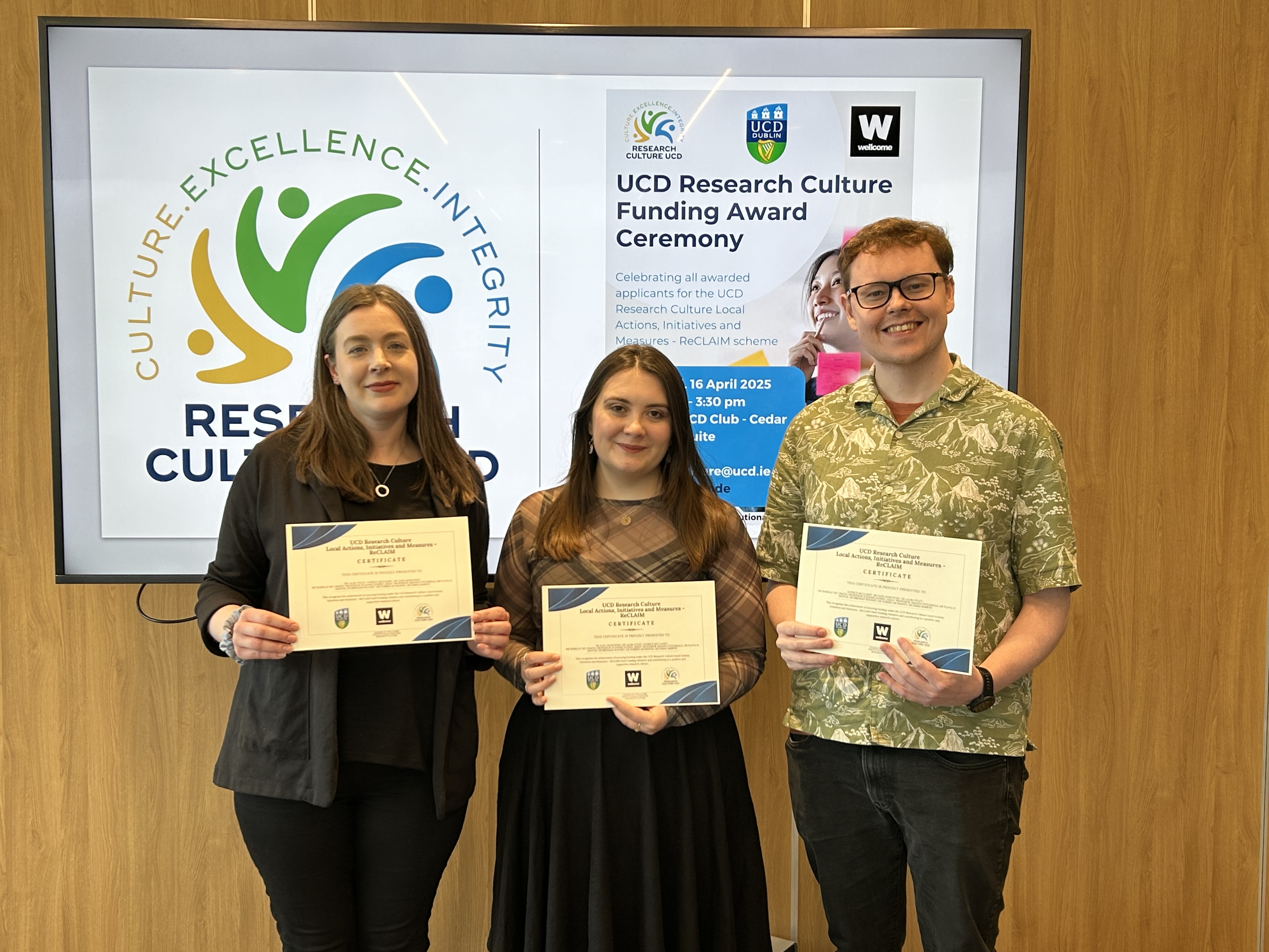 Three researchers holding a certificate and smile for the camera